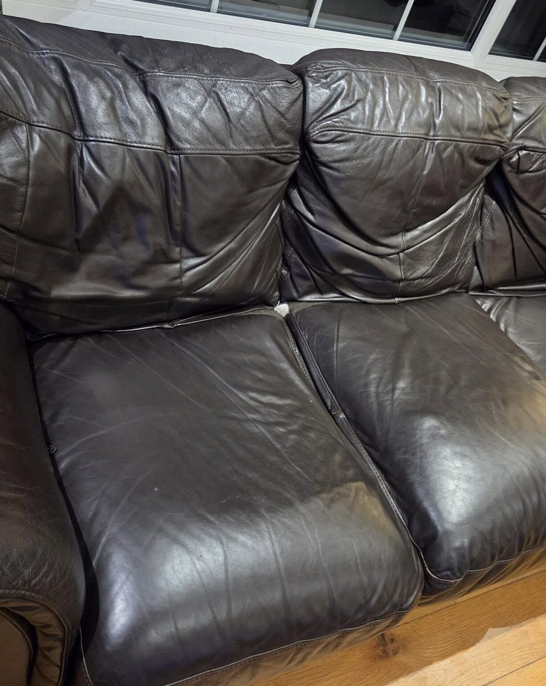 Close-up of a worn black leather sofa before repair